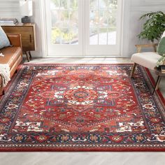 a large red rug with an intricate design on the floor in front of a window