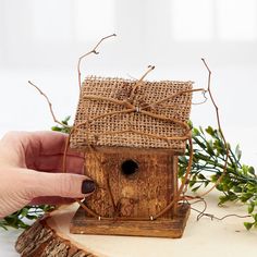 a hand holding a birdhouse made out of wood