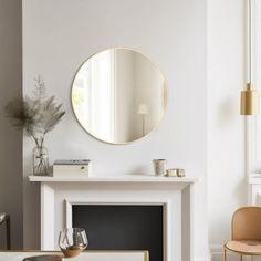 a living room filled with furniture and a round mirror on the wall above a fireplace