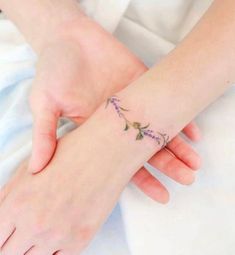 a woman's hand with a flower tattoo on her left wrist and the other arm