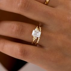 a woman's hand with two gold rings on it and a diamond ring in the middle