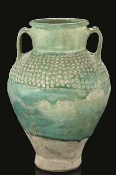 a green and white vase sitting on top of a table