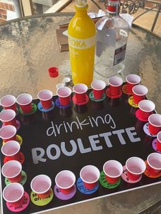 a table topped with lots of cups and a sign that says drinking roulette