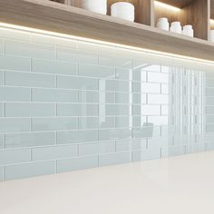 a white counter top sitting under a shelf next to a light blue tiled kitchen wall