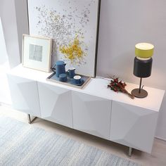 a white sideboard with two blue vases on it and a lamp next to it