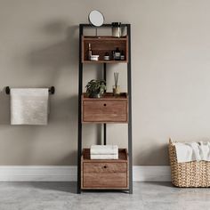 a wooden shelf with two drawers next to a towel rack and basket on the floor