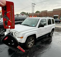 a white jeep parked in a parking lot next to a red and black car tag