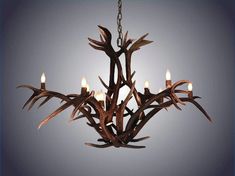 a chandelier made out of antler branches with lit candles in the center