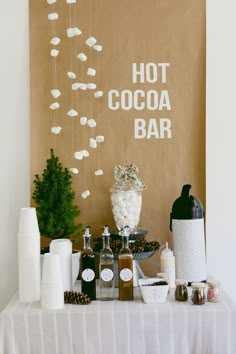 a table topped with lots of bottles and condiments next to a sign that says hot cocoa bar