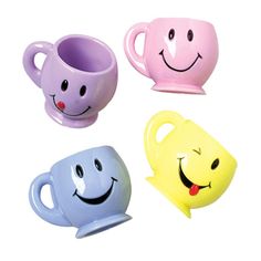 four different colored coffee mugs with faces on them