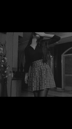 black and white photograph of a woman standing in a living room with her hands behind her head