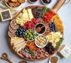 a platter filled with different types of cheeses, crackers, and fruit