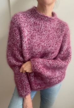 a woman is wearing a pink sweater and posing for the camera with her hands on her hips