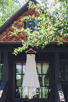 a wedding dress hanging on the front door of a house with trees in the background