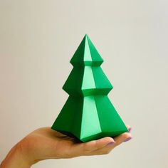 a hand holding a green origami christmas tree on it's left side