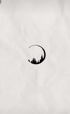 a black and white photo of a crescent moon with trees in the background on paper