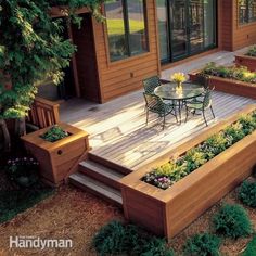 an outdoor patio with wooden steps and planters on the deck, surrounded by greenery