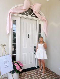 a woman standing in front of a white door with pink bows on it's head