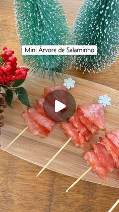 several skewered meats on sticks with pine cones and red flowers in the background