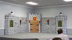 a man sitting on a stage in front of a castle made out of cardboard boxes