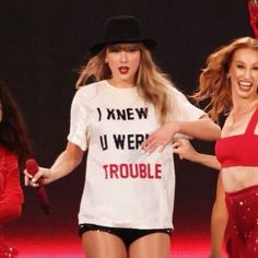 two women in red and white outfits on stage with one holding a microphone while the other holds