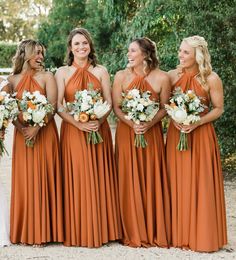 a group of women standing next to each other wearing dresses and holding bouquets in their hands