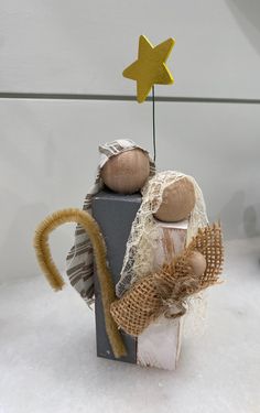 a small wooden angel sitting on top of a box filled with burlap and twine