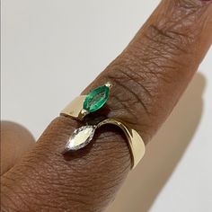 a close up of a person's hand with a ring on it and an emerald stone