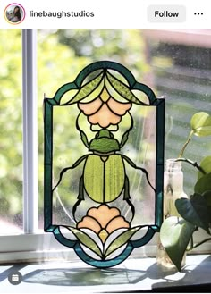 a stained glass window with a lady bug on it's side and green leaves in the background