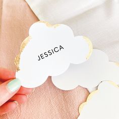 a person holding up a white and gold cloud shaped name tag with the word jessica on it