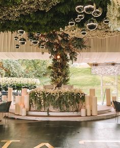 an outdoor ceremony setup with candles and greenery on the altar, surrounded by hanging chandeliers