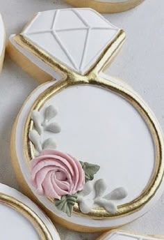 decorated cookies with white and pink frosting on top of each other in gold trimmings