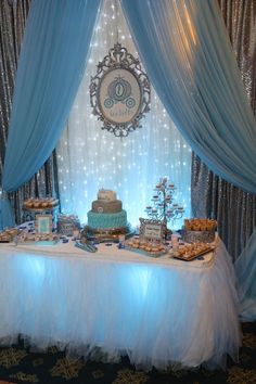 a table topped with lots of desserts under a blue drapeed curtain covered wall