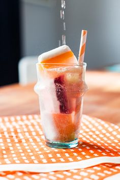 a glass filled with ice and fruit on top of a table