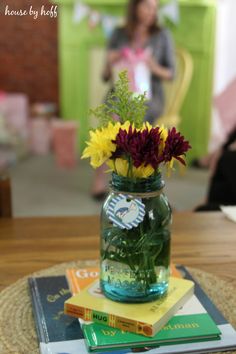 a vase filled with flowers sitting on top of a table next to books and magazines