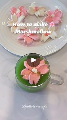 a green cup filled with marshmallows sitting on top of a table next to a white plate