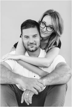 black and white photograph of a man hugging a woman's back while she is wearing glasses