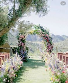 an outdoor ceremony setup with flowers and greenery on the aisle, in front of mountains