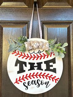 a baseball door hanger with the words tise season painted on it and flowers