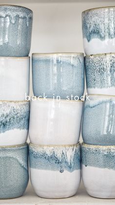 a stack of blue and white cups sitting on top of each other in front of a shelf