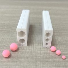 two white plastic objects with pink balls on the floor