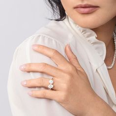 a woman wearing a white shirt and diamond ring on her left hand, looking at the camera