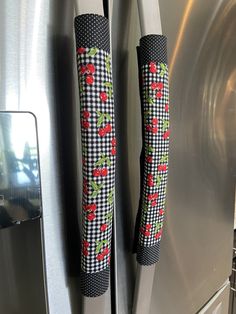 a close up of the handles on a stainless steel refrigerator with red flowers and leaves