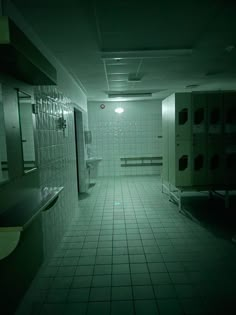 a dimly lit bathroom with urinals and sinks in the middle of the room