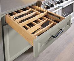 an open drawer in a kitchen with utensils and spoons on the drawers