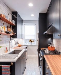 a kitchen with black cabinets and wooden counter tops