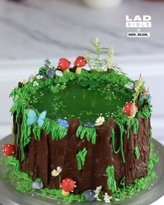 a cake decorated with grass and flowers on a plate, sitting on a table top