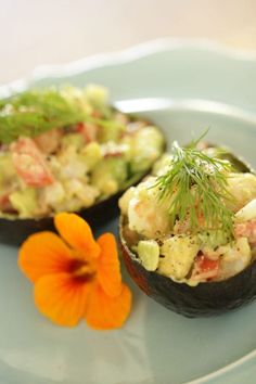 two stuffed avocados on a plate with a flower