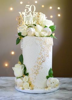 a white and gold wedding cake with flowers on top