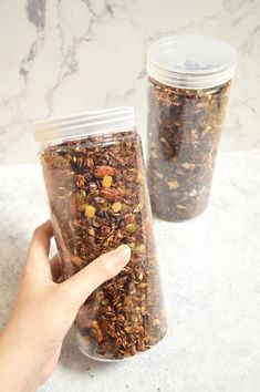 two jars filled with granola sitting on top of a counter next to each other